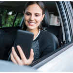Nova Lei TVDE em Portugal: Regras, Contabilidade e Seguros Motorista TVDE em Portugal dentro do carro, segurando um smartphone com aplicativo de transporte aberto.